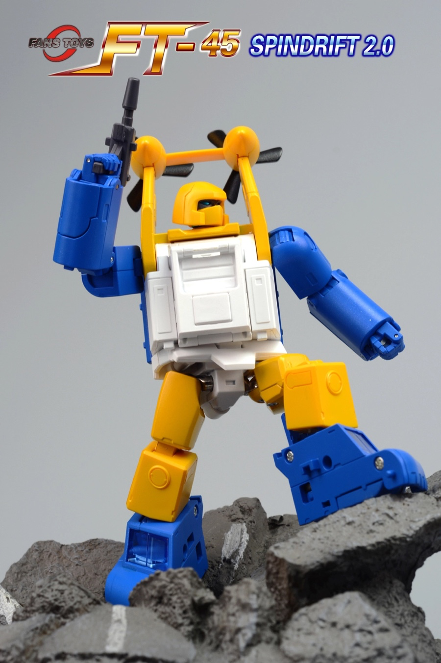 A toy robot figure in blue, yellow, and white stands on gray rocks against a plain gray background, with the text 'FT-45 SPINDRIFT 2.0' and a small 'FLEYSYSTEMS' logo at the top left.