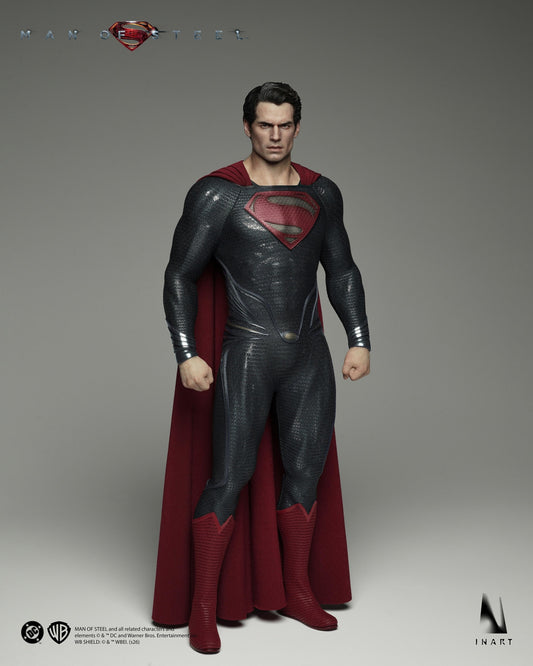 A highly detailed collectible action figure of Superman from Man of Steel, posed against a neutral gray studio background. The figure features textured dark gray armor, a deep red cape, and red boots, with a printed red and blue S-shield on his chest.