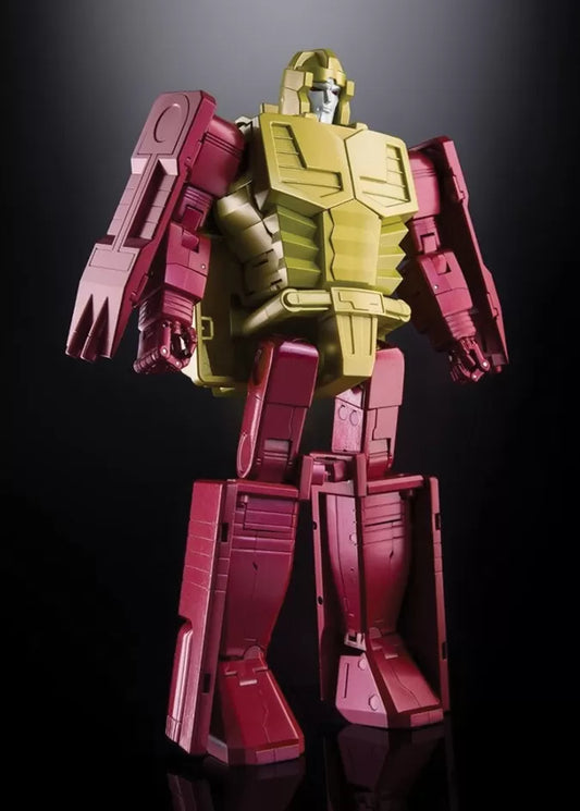A Transformers-style robot action figure or collectible model standing upright against a dark studio background. The figure has a metallic gold torso and head with deep pinkish-red arms, shoulders, and legs.